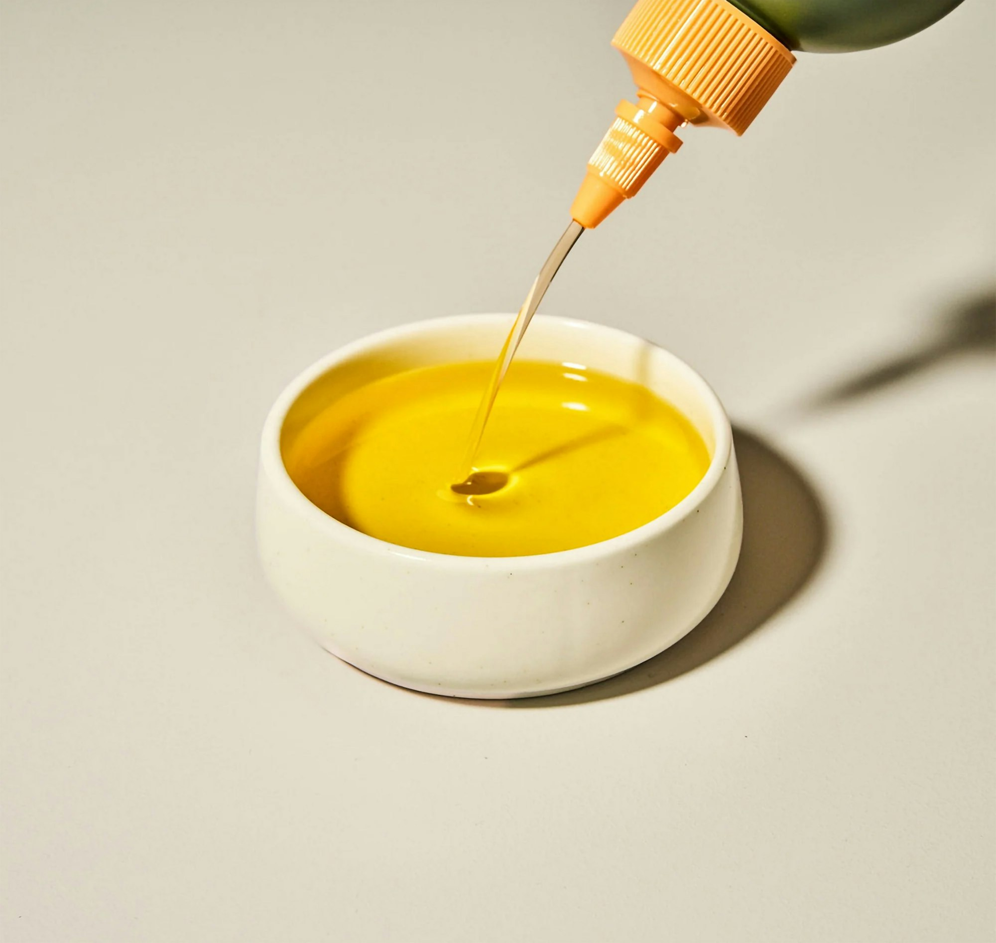 Yellow coloured spice oil getting poured into a little bowl.