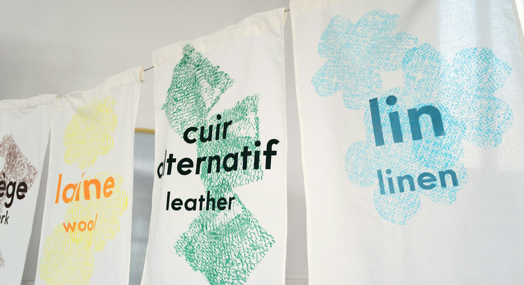 Photography of screen-printed cotton textiles in yellow, blue, green, brown.