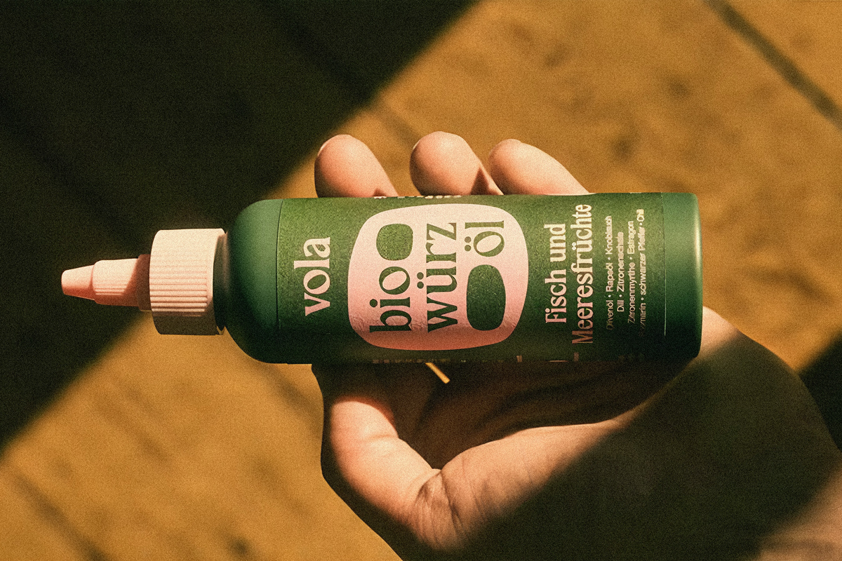 New packaging for vola hold by a hand in front of a wooden floor.